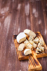 Pieces of various cheese on a board. Cheese plate. Selective focus. Copy space