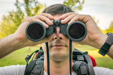 Traveler man looks through a binoculars