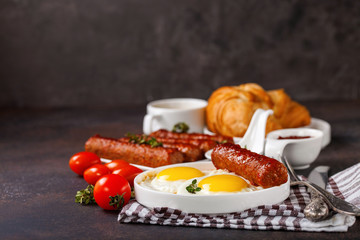 Breakfast - Fried eggs and meat sausages and sauces against a dark background. Selective focus. Copy space
