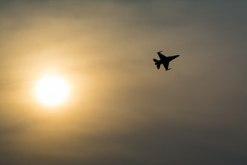 Silhouette of jet fighter at sunset