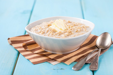 Porridge with oil in a bowl on a blue wooden background. Healthy breakfast. Selective focus. Copy space