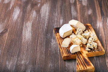 Pieces of various cheese on a board. Cheese plate. Selective focus. Copy space
