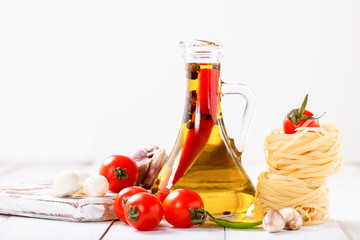 Olive oil with pepper in a bottle, paste, cheese and tomatoes on a light background. Selective focus. Copy space