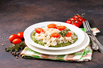 Paste with tomatoes and spinach sauce in a plate on a table. Selective focus. Copy space