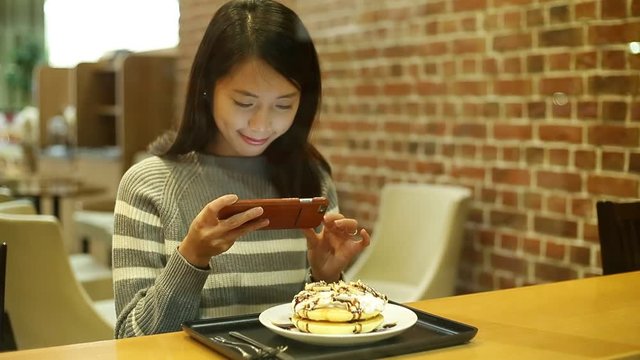Woman taking photo on dessert in coffee shop