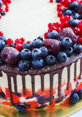 Bright festive cake with berries and chocolate on a white wooden background