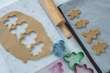 A Family Of Gingerbread Cookies Cut out of Cookie Dough On Marble Slab - Horizontal from Above