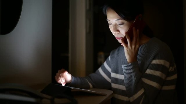 Woman using tablet computer and talk to mobile phone at home