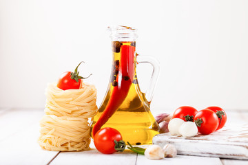 Olive oil with pepper in a bottle, paste, cheese and tomatoes on a light background. Selective focus. Copy space