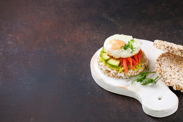 Crispbread with avocado, egg and a salmon against a dark background. Healthy breakfast. Selective focus. Copy space