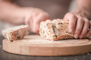 fresh bread in hands closeup on old wooden background