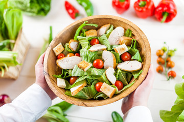 hands holding an healthy checken salad in a bowl