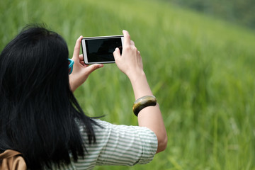 Woman traveler using smart phone to shoot green landscape view background, travel and lifestyle concept