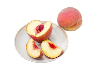 Whole peach and sliced peach on a saucer