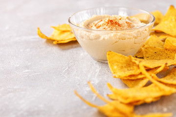 Hummus and nachos on a gray background.