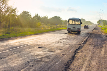 Crossing the junction of an old bay highway road with potholes and pits in a new one with a newly laid new road pavement with an asthalf photographed in the bright sun in the morning or dinner