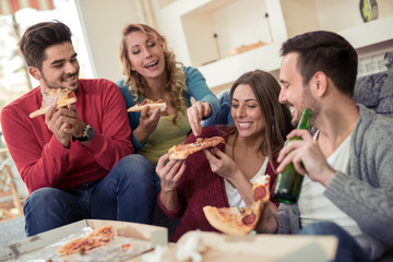 Happy friends eating pizza at home.