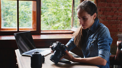 Naklejka na ściany i meble Portrait of a girl photographer working with a computer