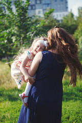 A little girl with her mother on a walk in the spring garden, socialize, laugh, embrace, rejoice, mother and daughter