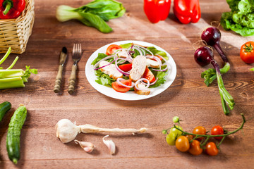 Fresh salad with chicken, tomato and greens on wooden background top view. Healthy food.
