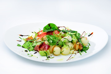 classic Italian summer delicious fresh salad with cheese, parma ham and soy sauce on white plate, on light background