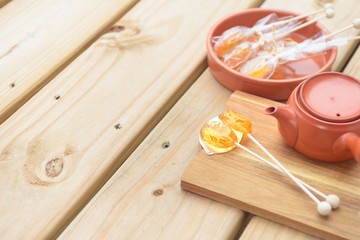 Candy lollipop and teapot on wooden background