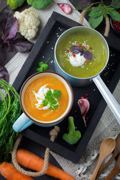 variety of vegetarian soups  cream of carrot and broccoli cabbage on a dark concrete background. Selective focus. Top view. Copy space.