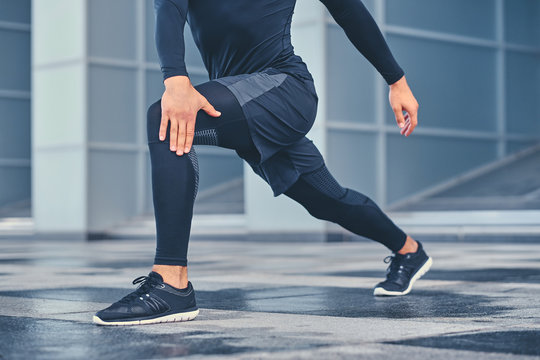 Sporty male is stretching his legs outdoors.