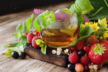 Hot herbal tea with fresh summer berries and herbs