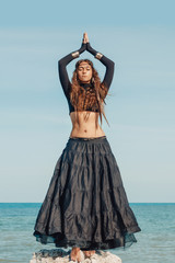 Attractive young woman in black dress on the beach. belly dancer. tribal fusion