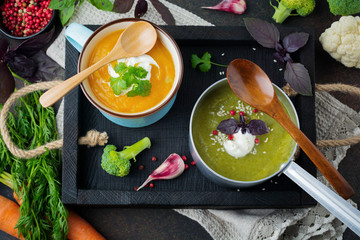 variety of vegetarian soups  cream of carrot and broccoli cabbage on a dark concrete background. Selective focus. Top view. Copy space.
