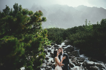 bride with the beautiful blue dress and groom with views of the beautiful green mountains and lake with blue water