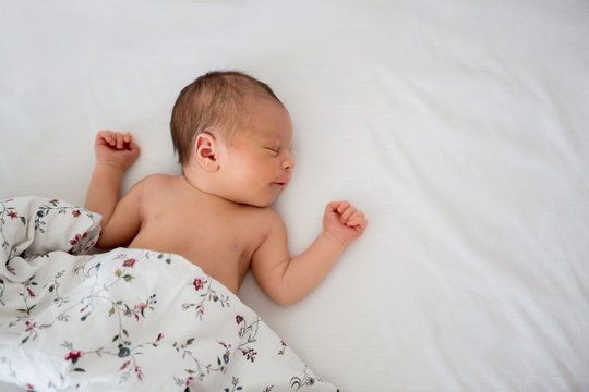 Beautiful Newborn Baby Boy In Bed. Infant Lying Down In Bed