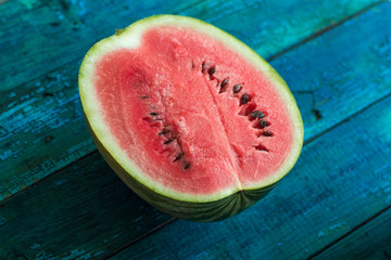 Fototapeta na wymiar half of watermelon on a bright blue wooden background