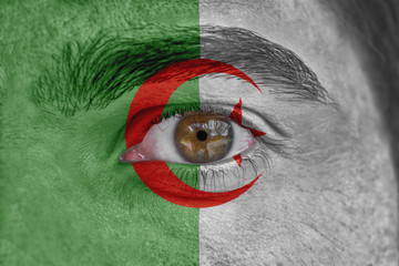 Human face and eye painted with flag of Algeria