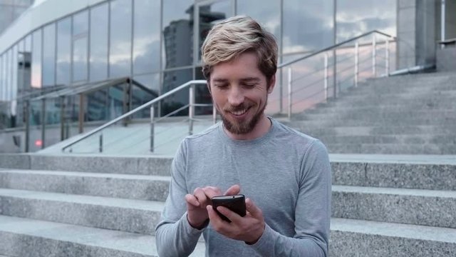 Young happy man touch a smartphone in city