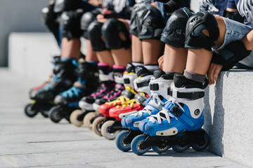 Feet of rollerbladers wearing inline roller skates sitting in outdoor skate park, Close up view of...