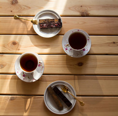 Cup of tea and chocolate on wooden table. Top view.