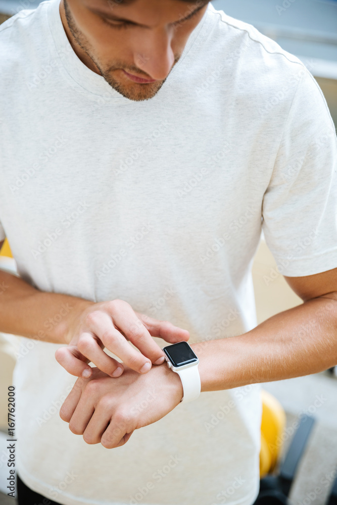 Wall mural Concentrated young sports man looking at watch