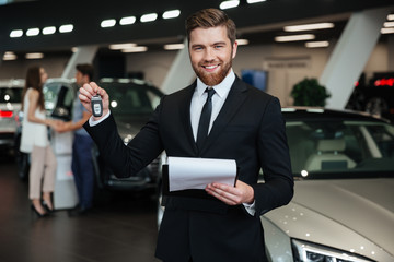 Fototapeta na wymiar Handsome man standing near car in car dealership