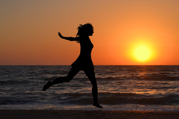 Fototapeta na wymiar Happy woman jumping in sea sunrise