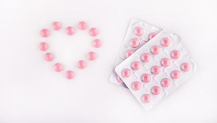 Pink tablets. Heart of pills. Pink vitamins in a blister on a white background. Copy space