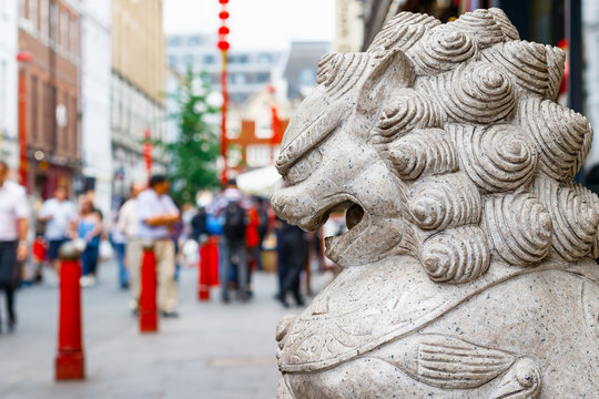 A guardian lion statue located in the crowded London Chinatown