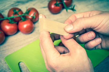 Woman apply plaster on her finger - injury in kitchen