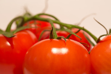 Up close view of red healthy tomatoes, two whole and one cut in half on white background.