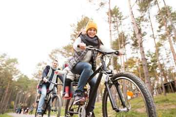 Fototapeta na wymiar Young family in warm clothes cycling in autumn park