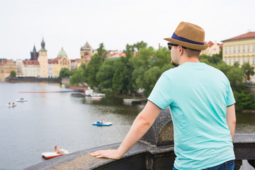 Back view of happy stylish tourist on Charles Bridge, Prague, Czech Republic. Handsome man...