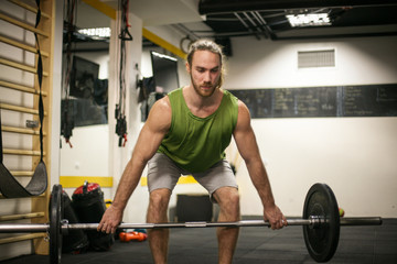 Naklejka na ściany i meble Young man in the gym. Young man in the gym lift weights.
