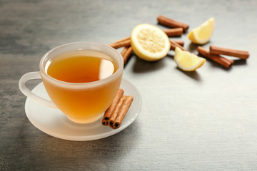 Cup with aromatic hot cinnamon tea and lemon on table