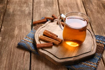 Photo sur Plexiglas Theé Planche de bois avec tasse de thé à la cannelle aromatique sur table